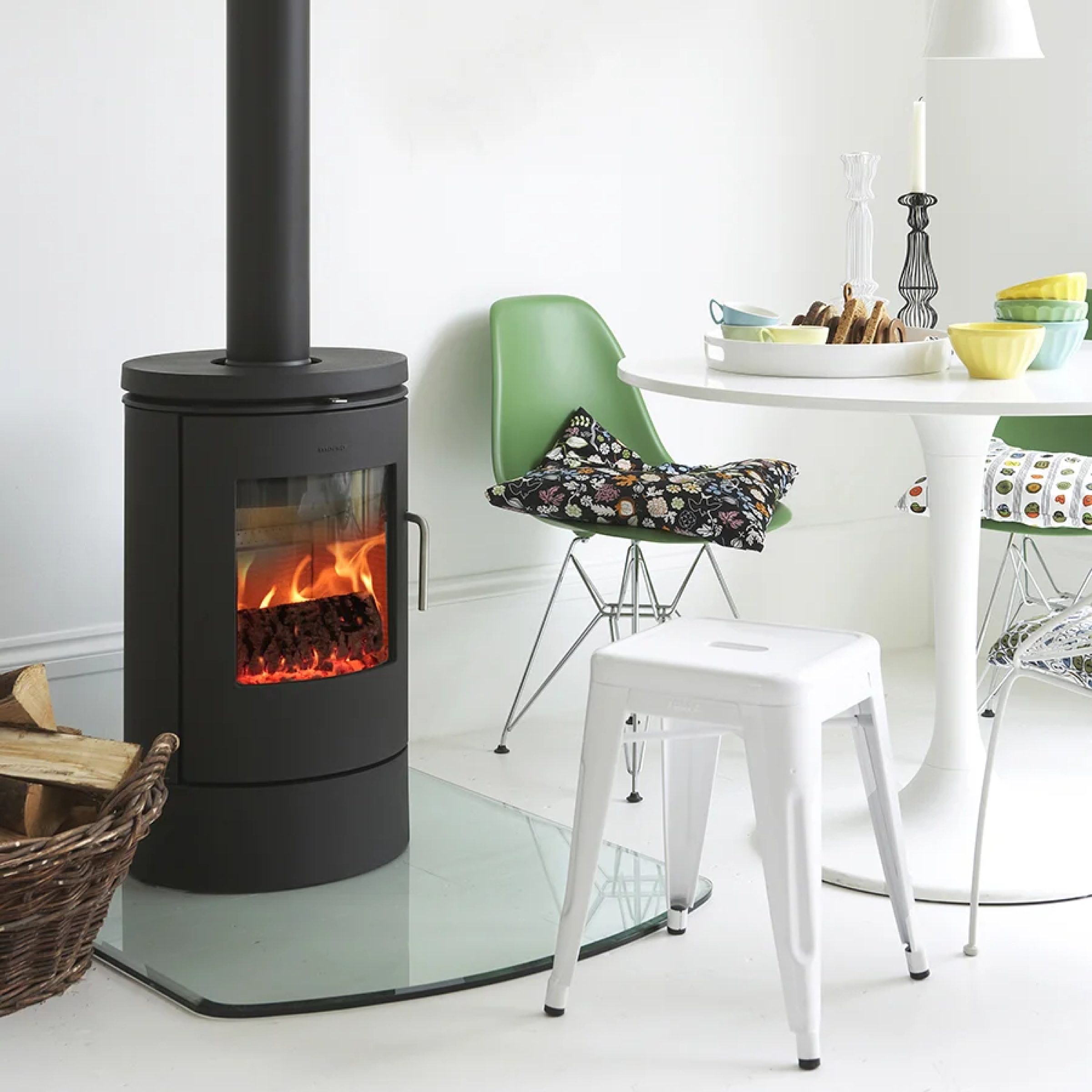 Black freestanding wood stove with chimney pipe, side door, and burning fire.