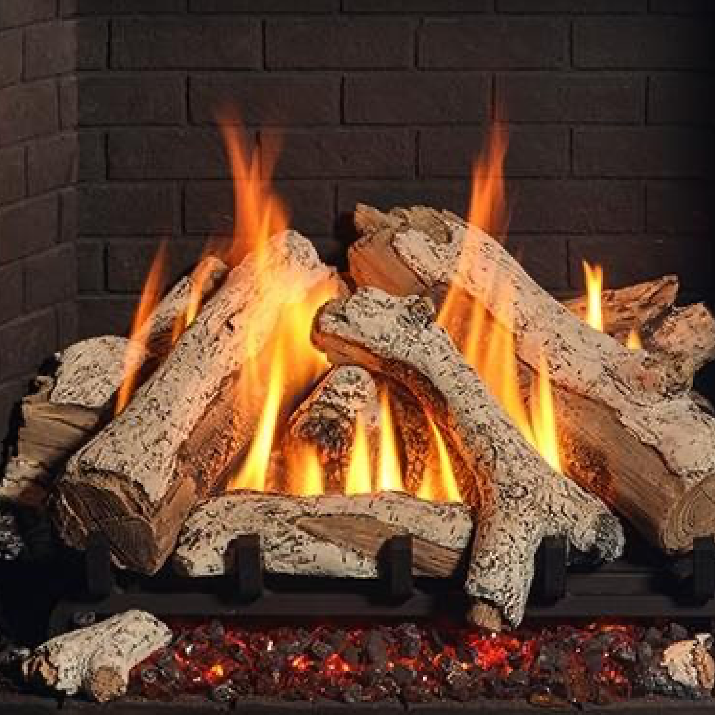 Birch log set with glowing fire and flames over dark log embers